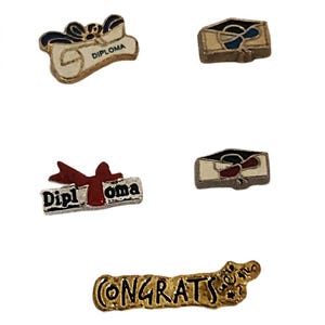 May include: A collection of graduation-themed pins. The pins include diploma scrolls, graduation caps, and a pin that says "CONGRATS". The pins are in gold, silver, red, white, and blue.