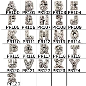 May include: A collection of silver-toned alphabet charms, each encrusted with clear rhinestones. The letters A through Z are displayed, with each charm having a unique design. Each charm is labeled with a product code.