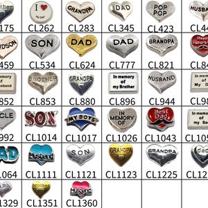 May include: A collection of various metal charms with text, including "brother," "dad," "son," and "grandpa." The charms are in heart, rectangular, and circular shapes, with some featuring colorful accents.