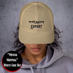 以下が含まれることがあります： ベージュのメッシュトラッカーハットに、「mental mapping EXPERT」という黒い刺繍のデザインが施されています。EXPERTの文字の下には赤と白の線が引かれています。