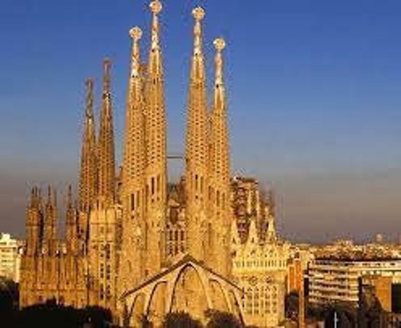 May include: A large, unfinished, beige-colored cathedral with multiple towers and spires. The building is made of stone and has a complex design.