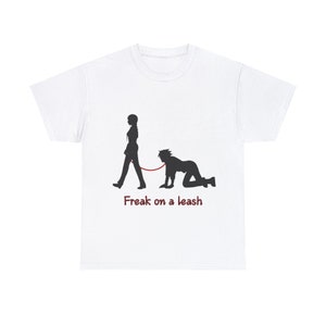 May include: White t-shirt featuring a black silhouette of a person walking a person on a leash. The text "Freak on a leash" is printed in red below the graphic. The shirt is made of a soft, comfortable material.