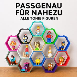 Könnte beinhalten: Ein mehrfarbiges, modulares, hexagonales Wandregalsystem mit verschiedenen kleinen Spielfiguren. Der Text oben lautet PASSGENAU FÜR NAHEZU ALLE TONIE FIGUREN. Die Regale sind in einem Wabenmuster mit leuchtenden Farben angeordnet.