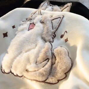 Close-up of singing cat and music note details on hoodie