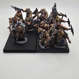 May include: A group of ten painted miniature figures of dwarves, each holding a weapon, standing on black bases. The dwarves are wearing armor and carrying axes, swords, and a banner.