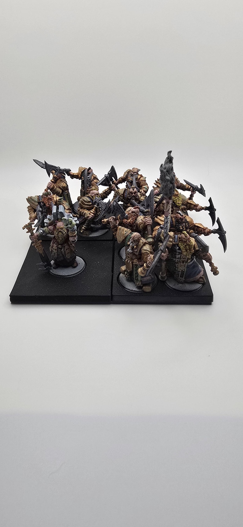 May include: A group of ten painted miniature figures of dwarves, each holding a weapon, standing on black bases. The dwarves are wearing armor and carrying axes, swords, and a banner.