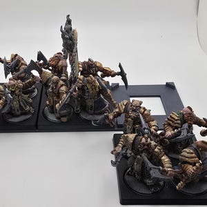 May include: A group of 12 painted miniature figures of warriors, each standing on a black base. The figures are wearing armor and carrying weapons, and they are arranged in a battle formation.