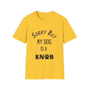 Peut inclure: Un t-shirt jaune vif à manches courtes avec le texte noir SORRY BUT MY DOG IS A KNOB imprimé sur le devant, où une petite empreinte de patte noire remplace la lettre O dans le mot KNOB, centré sur la poitrine.
