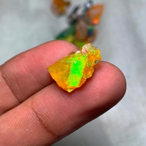 May include: A rough, irregular piece of opal with a bright yellow base and a green flash of color.