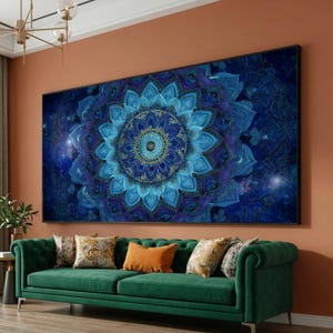 May include: Large, framed wall art featuring a detailed mandala design in shades of blue and gold. The artwork is displayed above a green sofa with decorative pillows, creating a vibrant and stylish living room setting.
