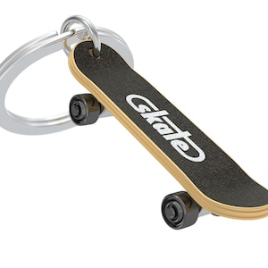 Könnte beinhalten: Miniatur-Skateboard-Schlüsselanhänger mit schwarzem Deck und dem Wort "Skate" in Weiß. Die Rollen sind schwarz, und der Schlüsselanhänger ist silberfarben. Das Skateboard hat einen naturfarbenen Holzrand.