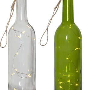 Op de afbeelding: Twee glazen flessen met kurken en touwhandvatten. Eén fles is helder en de andere is groen. Beide flessen bevatten een string met warm witte LED-lampjes.