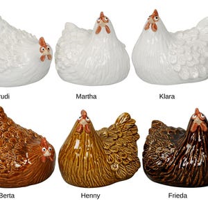 Könnte beinhalten: Sechs Keramik-Hühnerfiguren in Weiß, Braun und Gold. Jedes Huhn hat einen roten Kamm und Kehllappen. Die Hühner heißen Trudi, Martha, Klara, Berta, Henny und Frieda. Ideal für die Dekoration im Bauernhausstil.