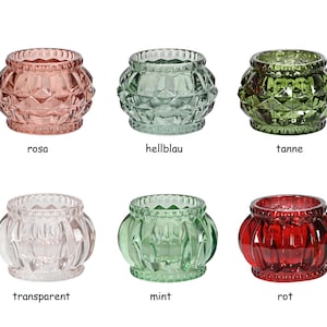 Könnte beinhalten: Sechs gläserne Kerzenhalter in verschiedenen Farben, darunter rosa, hellblau, grün, klar, mintgrün und rot. Jeder Halter hat ein strukturiertes, rautenförmiges Muster und einen perlenbesetzten Rand.