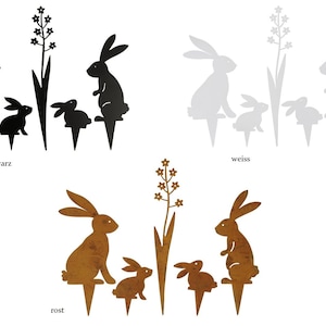 Könnte beinhalten: Set aus drei Metall-Hasensilhouetten in Schwarz, Weiß und Rost. Jede Silhouette zeigt eine Hasenmutter und zwei Hasenkinder. Die Hasen stehen neben einer stilisierten Blume.
