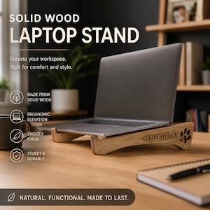 May include: A solid wood laptop stand with a light brown finish and the text CADYSHACK engraved on the side. The stand features a cutout paw print design, a smooth surface, and an angled base to support a silver laptop computer on a desk.