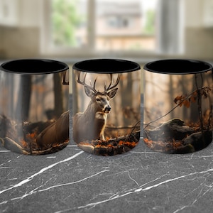 May include: Three black coffee mugs with a white deer in a forest scene printed on them. The deer is lying down in the forest with its head up and looking at the camera. The forest is filled with brown and orange leaves.