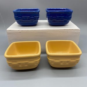 May include: Four square ceramic bowls with a basket-weave texture on the exterior. Two bowls are a deep royal blue, and two bowls are a soft yellow. Each bowl features a smooth interior and a raised, repeating woven pattern around the sides.