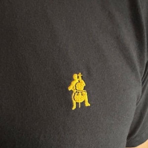 May include: A black t-shirt with a gold embroidered image of a person playing a cello.
