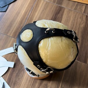 May include: Black leather head harness with silver buckles and rings. The harness is on a foam head form covered in plastic wrap.