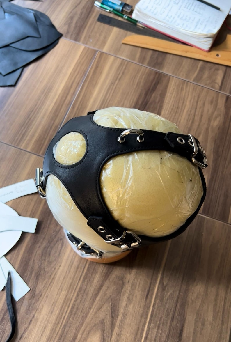 May include: Black leather head harness with silver buckles and rings. The harness is on a foam head form covered in plastic wrap.