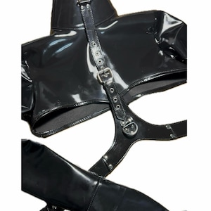 May include: Black patent leather harness with straps and buckles. The harness has a high collar and a cutout in the front.