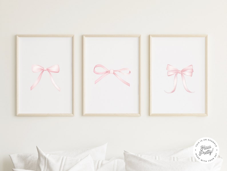 May include: Three framed prints with watercolor illustrations of pink bows. The prints are arranged in a row on a white wall.