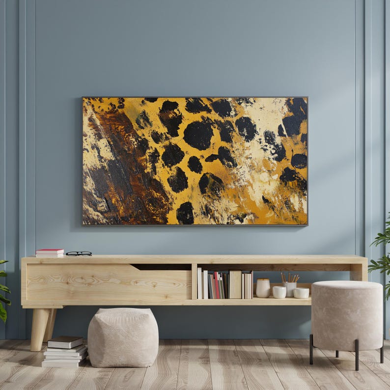 Puede incluir: Una consola de medios de madera con un caj&oacute;n y estantes, que presenta una pintura abstracta enmarcada de un patr&oacute;n de estampado de leopardo en tonos marrones, amarillos y negros. La consola est&aacute; en una habitaci&oacute;n con paredes de color azul claro y un suelo de madera clara.