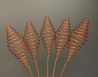 May include: Five copper-colored metal wire ornaments, each featuring a conical spiral shape attached to a straight stem. The wire coils are arranged in a fan-like formation, showcasing a metallic finish and a consistent, repeating geometric pattern.