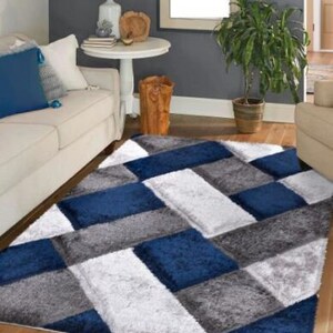 May include: A blue and gray area rug with a geometric pattern. The rug has a soft, plush texture and is perfect for adding a touch of modern style to any room.