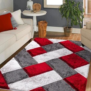May include: Red, white, and gray area rug with a geometric pattern. The rug has a soft, plush texture.