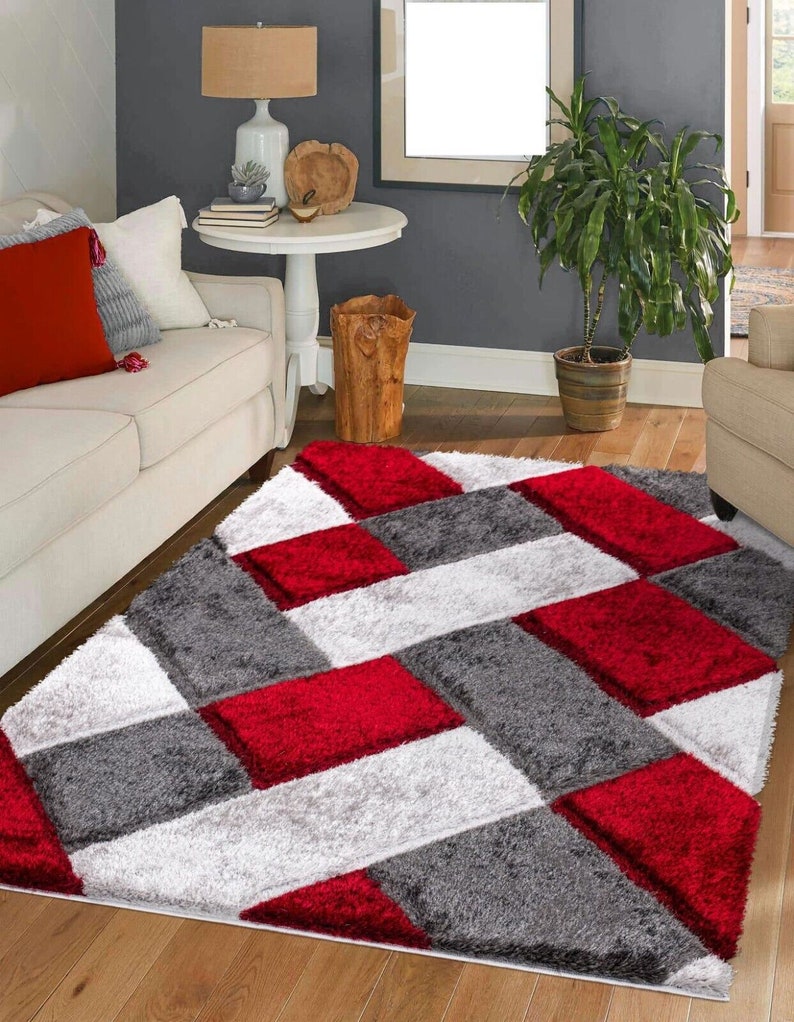 May include: Red, white, and gray area rug with a geometric pattern. The rug has a soft, plush texture.
