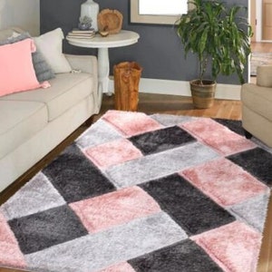 May include: A pink, gray, and black area rug with a geometric pattern. The rug has a soft, plush texture.