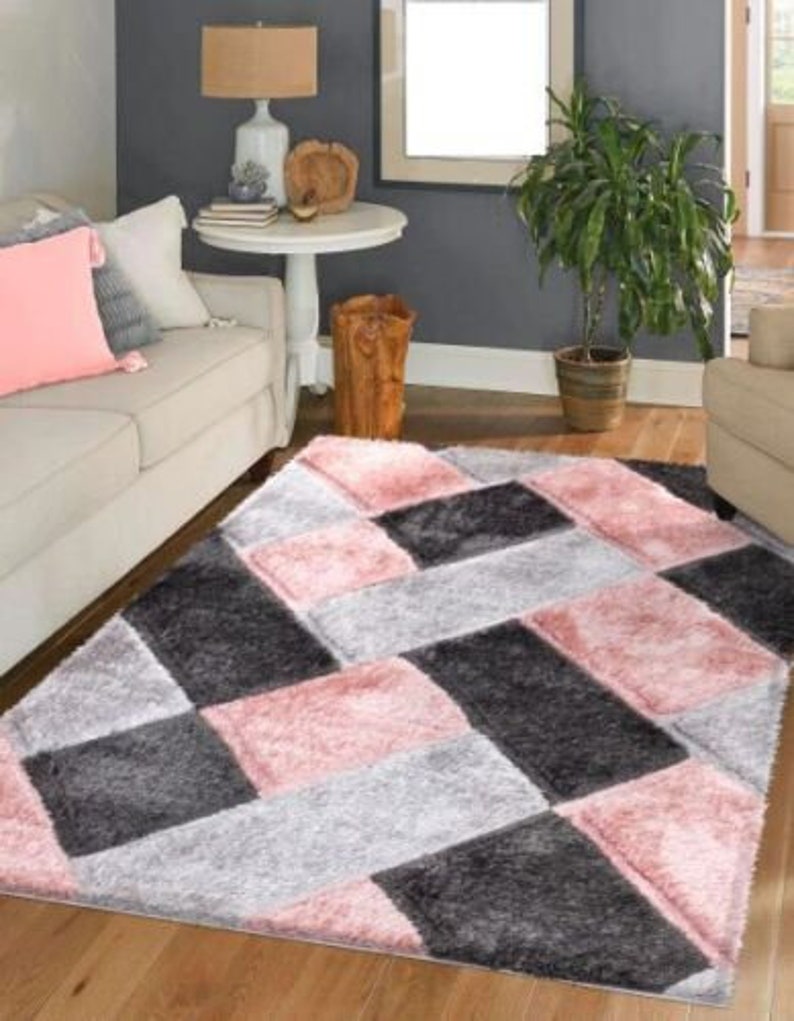 May include: A pink, gray, and black area rug with a geometric pattern. The rug has a soft, plush texture.