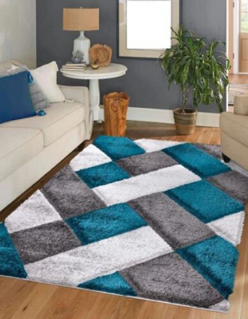 May include: A teal, gray, and white area rug with a geometric pattern. The rug has a soft, plush texture.