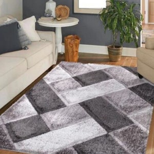 May include: A gray and white area rug with a geometric pattern. The rug has a soft, plush texture and is perfect for adding a touch of modern style to any room.