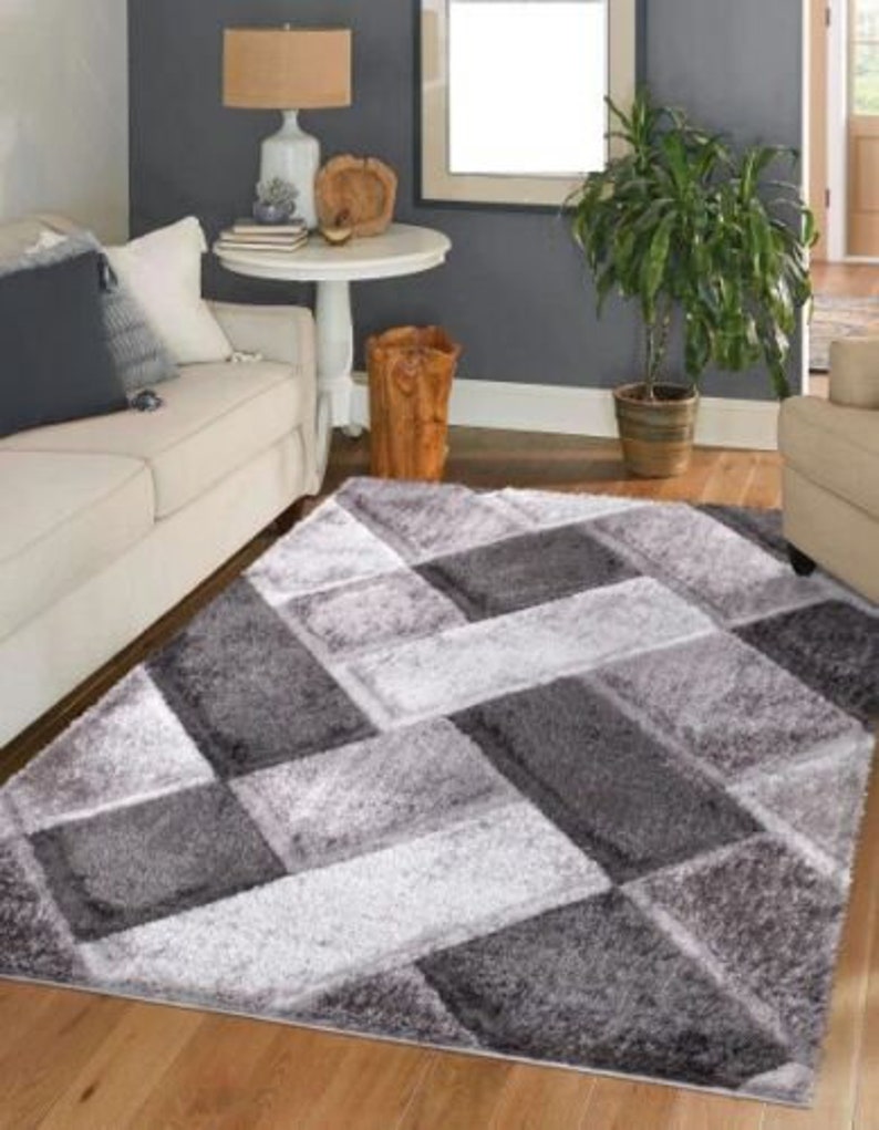 May include: A gray and white area rug with a geometric pattern. The rug has a soft, plush texture and is perfect for adding a touch of modern style to any room.