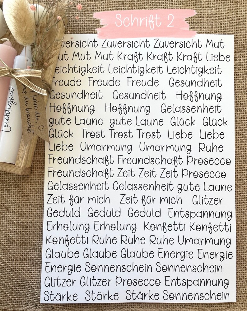 May include: A white card with black text listing positive words and phrases, including "Zuversicht", "Mut", "Kraft", "Liebe", "Freude", "Gesundheit", "Hoffnung", "Gl&uuml;ck", "Trost", "Umarmung", "Freundschaft", "Zeit", "Gelassenheit", "Geduld", "Erholung", "Konfetti", "Ruhe", "Glaube", "Energie", "Sonnenschein", "Glitzer", "Prosecco", "Entspannung", and "St&auml;rke".