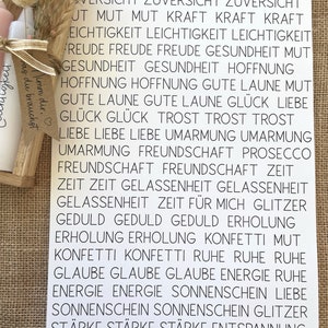 May include: A white sheet of paper with black text listing positive words and phrases in German. The words are arranged in columns and include words like "Mut" (courage), "Freude" (joy), "Hoffnung" (hope), "Liebe" (love), and "Gl&uuml;ck" (happiness).