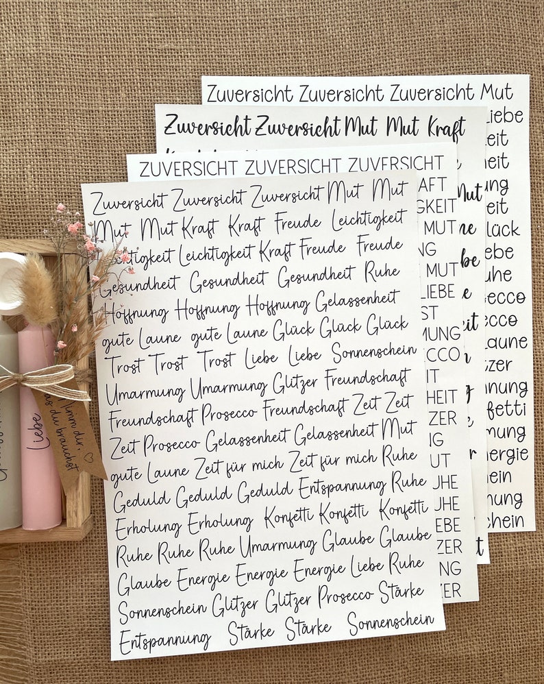 May include: White paper cards with black text, featuring positive words and phrases like "Zuversicht", "Mut", "Kraft", "Liebe", "Freude", "Gesundheit", "Hoffnung", "Sonnenschein", "Entspannung", "St&auml;rke", and "Gl&uuml;ck".
