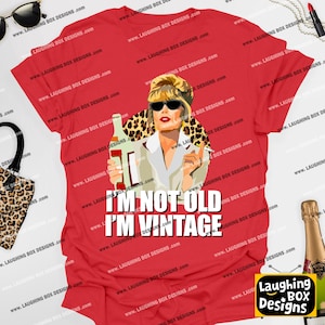 May include: Red t-shirt featuring a graphic of a woman in sunglasses holding a bottle and cigarette, with the text "I'm Not Old I'm Vintage". The design includes a leopard print background.