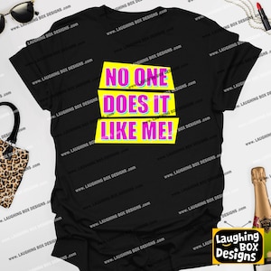 May include: Black t-shirt with the text "NO ONE DOES IT LIKE ME!" in pink and blue lettering on a yellow background. The shirt is a casual wear item.