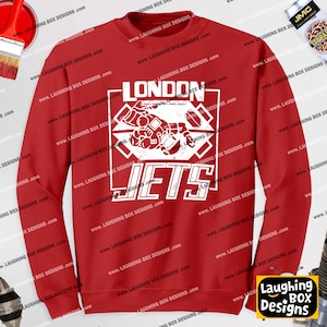 Könnte beinhalten: Ein rotes langärmeliges Sweatshirt mit Rundhalsausschnitt und einem weißen Grafikdruck auf der Brust. Das Design zeigt den Schriftzug LONDON JETS über und unter einer stilisierten Abbildung eines Düsenflugzeugs in einem rechteckigen Rahmen.