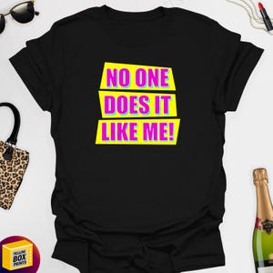 May include: Black t-shirt with a yellow and pink graphic that says "No one does it like me!"