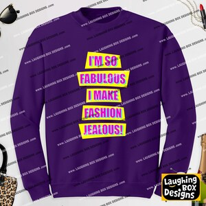 May include: A deep purple long-sleeve sweatshirt featuring the text I'M SO FABULOUS I MAKE FASHION JEALOUS! printed in bright pink letters on four stacked yellow rectangular shapes with a blue outline, centered on the front of the garment.
