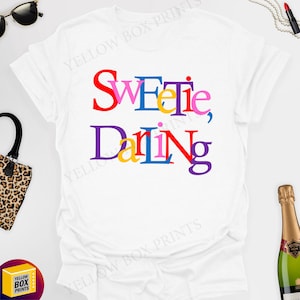 May include: White t-shirt with the text "Sweetie, Darling" in colourful letters.