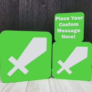 May include: Two green square signs with a white sword graphic. The smaller sign has the text "Place Your Custom Message Here!" on it.