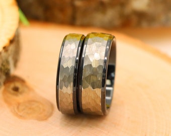 May include: Two black and silver wedding bands with a hammered finish. The bands are stacked on top of each other.