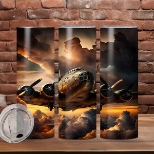 Könnte beinhalten: Drei Edelstahlbecher mit einem Vintage-Flugzeug, das durch Wolken fliegt, und einem Sonnenuntergang im Hintergrund. Die Becher sind perfekt, um Ihr Lieblingsgetränk zu genießen.