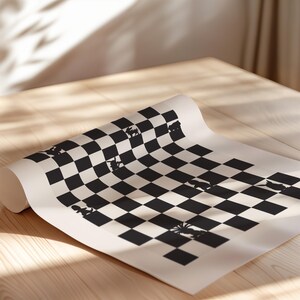 May include: Rolled-up black and white checkered chess board with chess piece silhouettes. The board is on a light-colored wooden surface, with shadows from a nearby window. The chess board is partially unrolled.